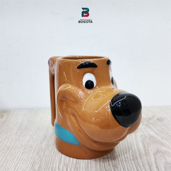 Mug Scooby-Doo 3D de cerámica; vista frontal tres cuartos con nariz en relieve y acabado brillante sobre mesa de madera.