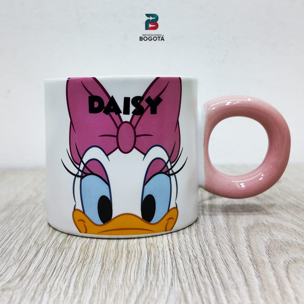 Mug Daisy Rosa de cerámica blanca con asa rosa y rostro de Daisy Duck; moño rosa y texto “DAISY”.