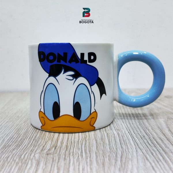 Mug Donald Azul de cerámica blanca con asa azul y rostro de Donald Duck; texto “DONALD” en azul.